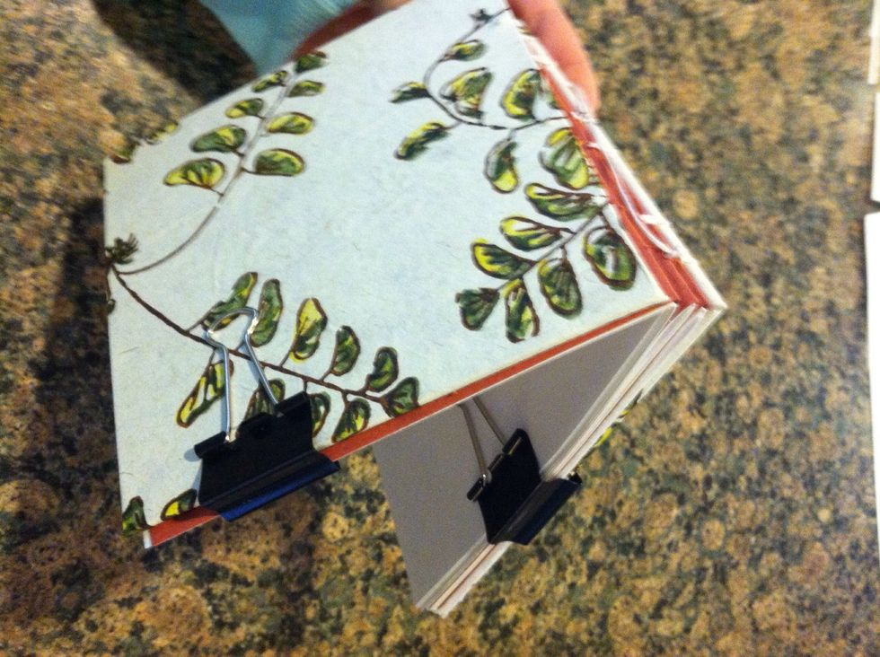 Put one binding clip on one side to hold next signature the other should be in the back cover and the last signature