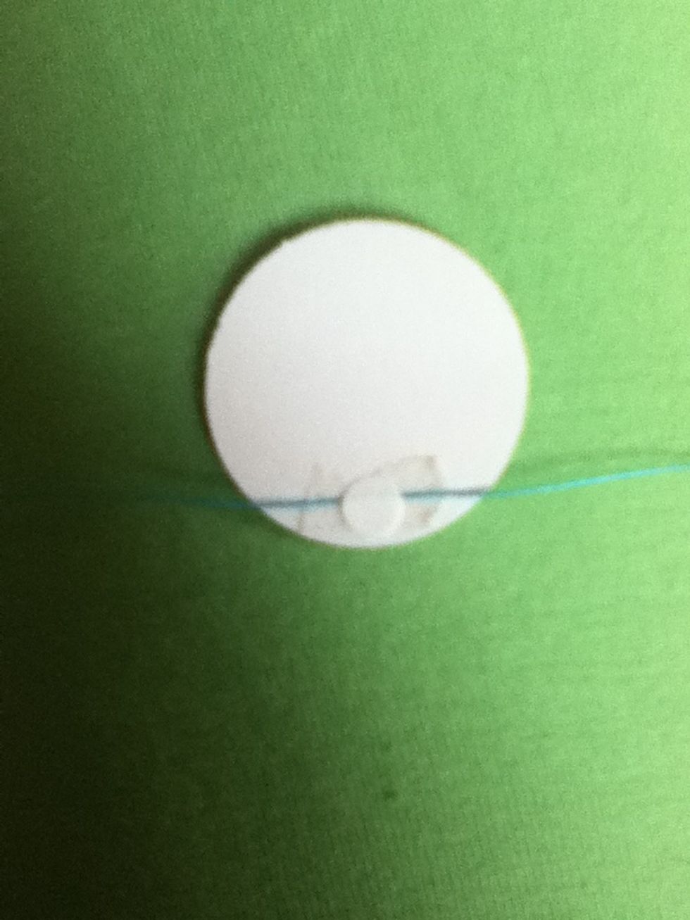 Put one of your scrap paper circles on to the tape and string to make a sandwich, and press down so that everything sticks together.