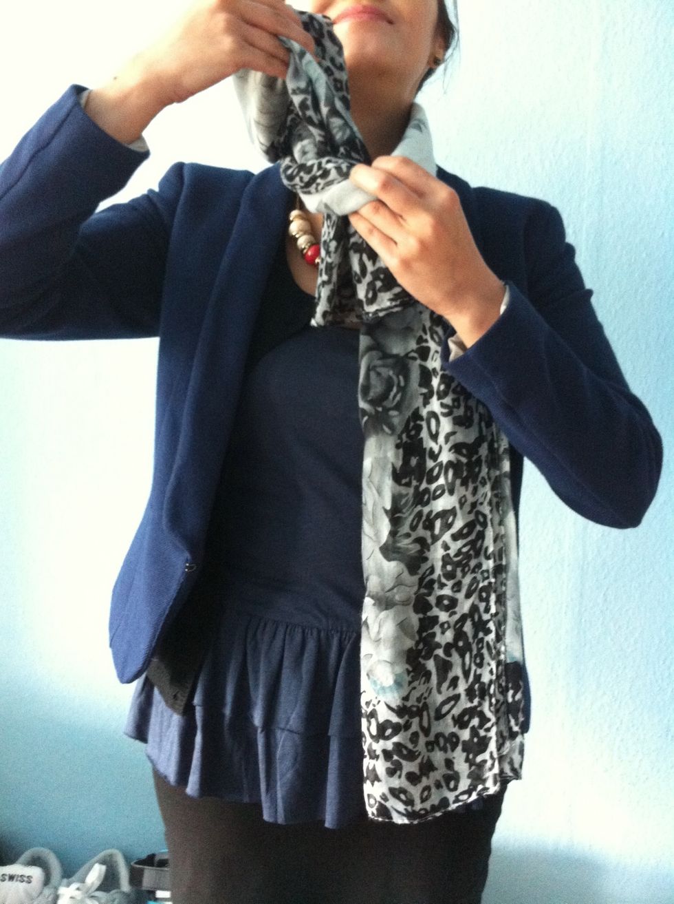 Put one side into the gap of the scarf...