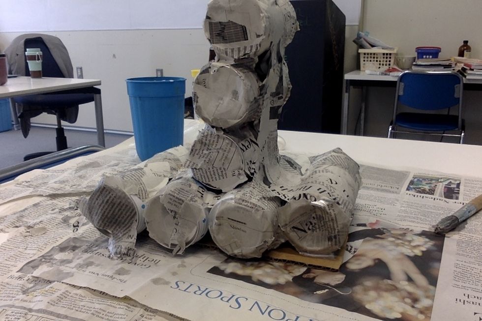 put paper mach\u00e9 on the cans and try to make as little amount of cans visible