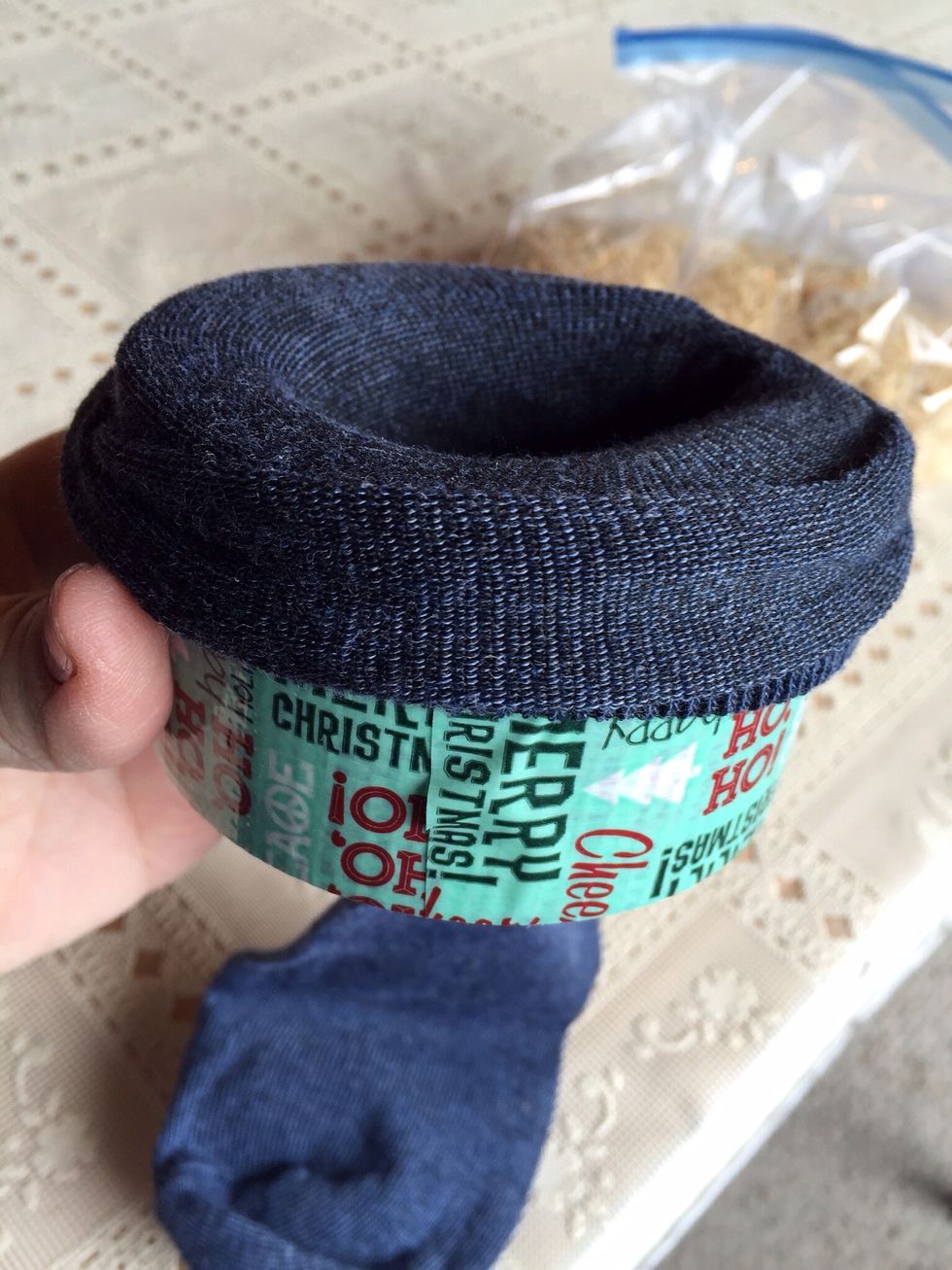 Put sock over the edge of the roll of tape. (You've just made an easy funnel!)
