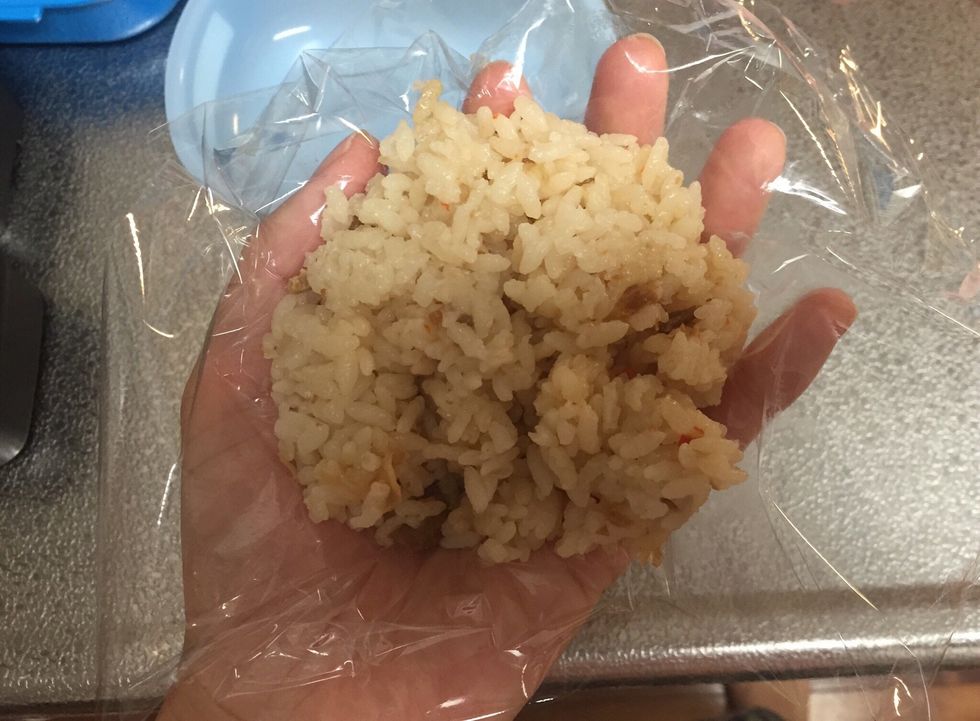 Put some brown rice on plastic wrap. This is chicken rice made with soy sauce.