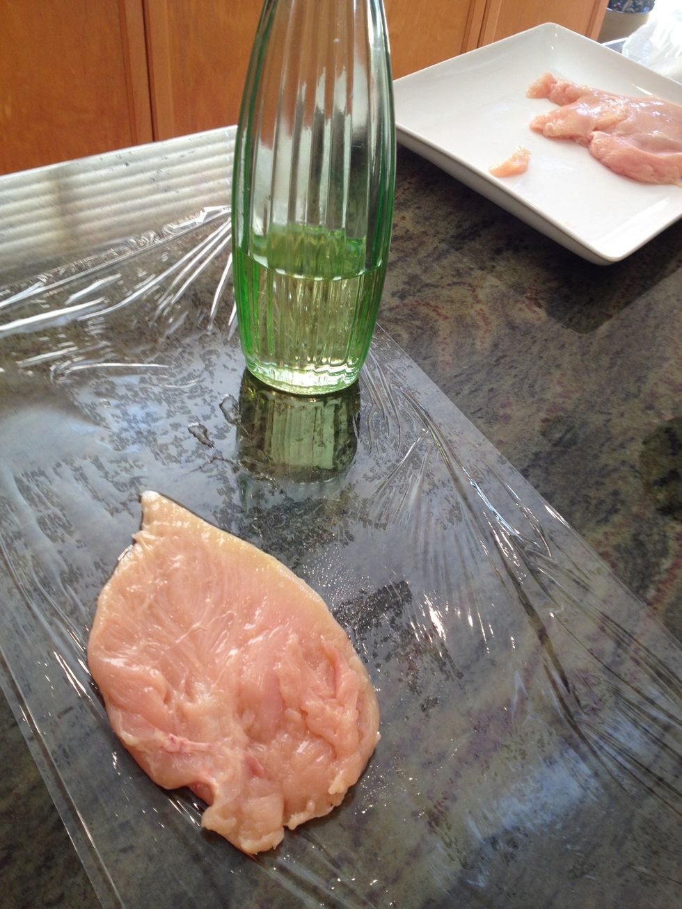 Put some olive oil on the saran wrap and then lay chicken breast on top of olive oil