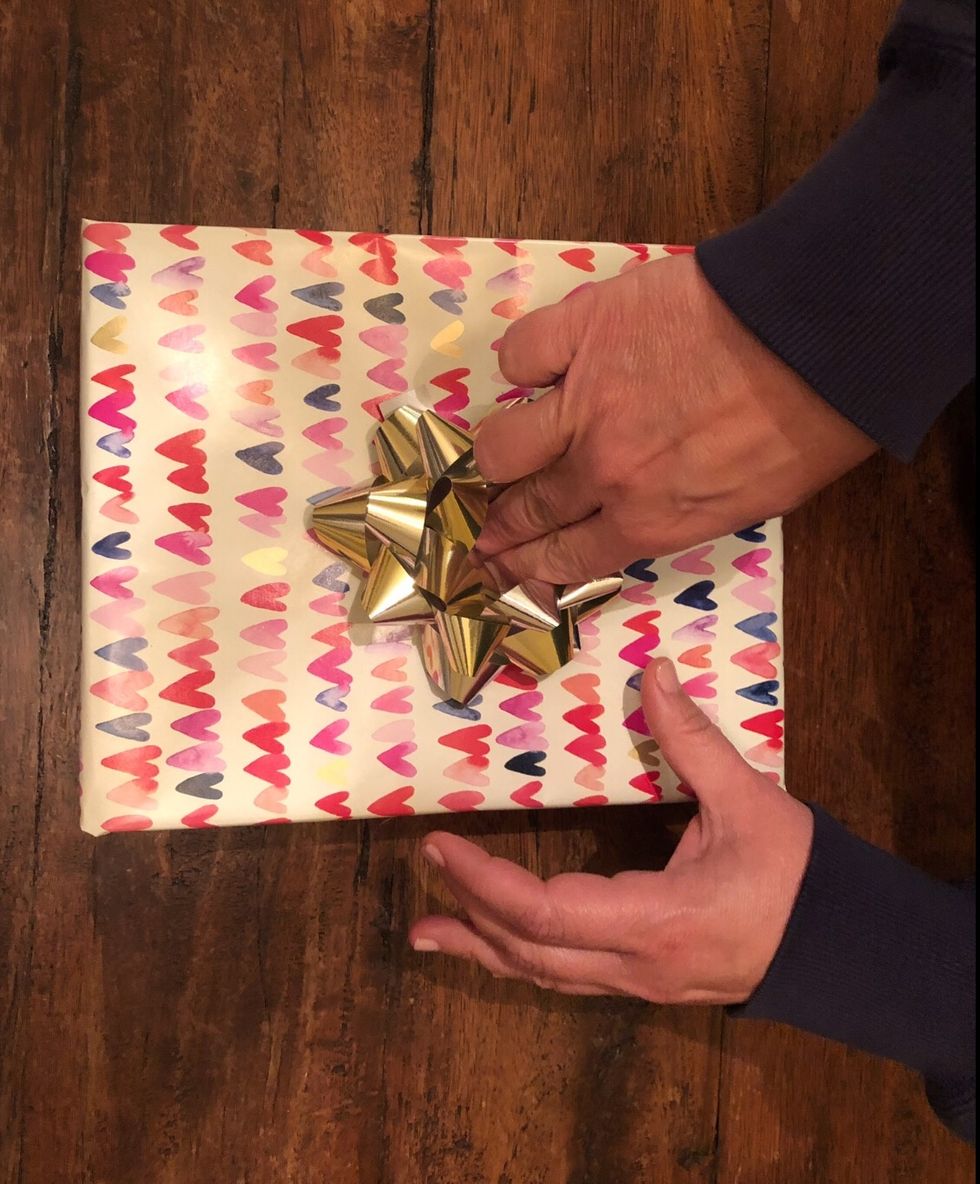 Put tape on the bottom of the bow and adhere it to the middle of the present.