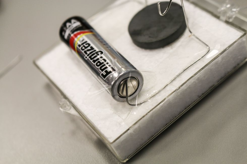 Put the battery between them. Adjust/bend the wires to fit well then tape them down tightly against the battery.