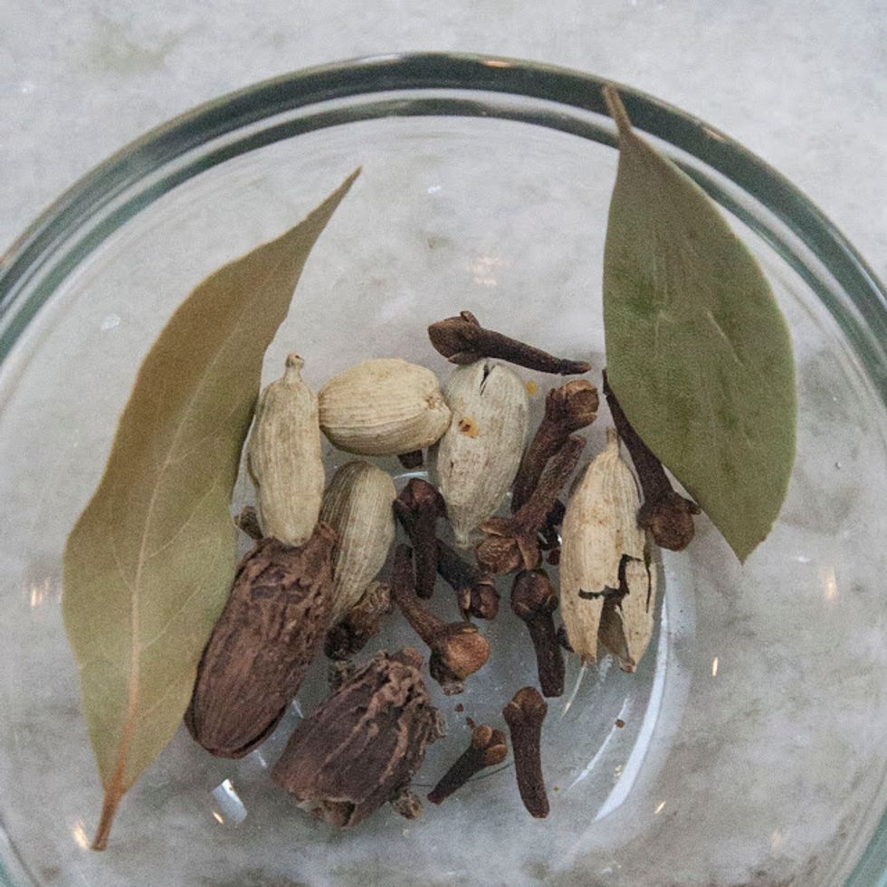 Put the black cardamom pods and the green cardamom pods in a mortar and crush them gently. You just want to crack the pods slightly.