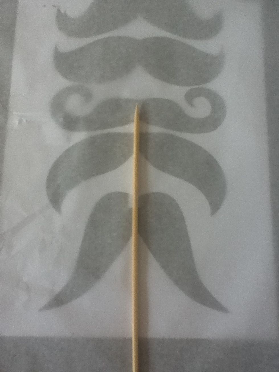 Put the butter paper over the mold (you can put the mold in a tray for easy handling) then put the stick (longer than a toothpick) in the center of the mustache.Hold the paper and the stick with tape.