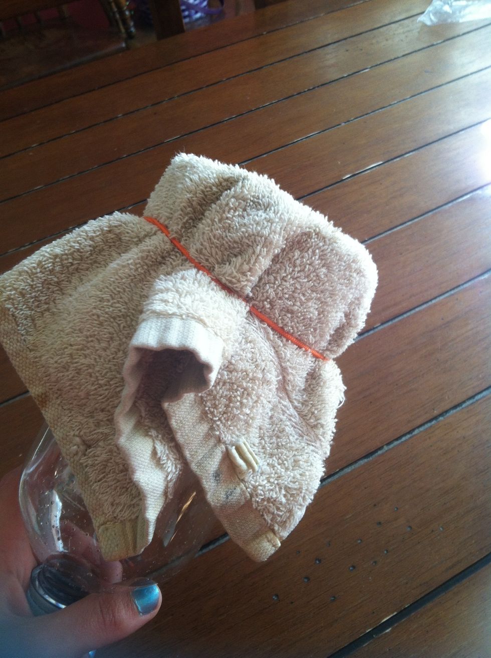 Put the cloth on the bottom of the bottle(on the side you cut off) and tie it on with the rubber band.
