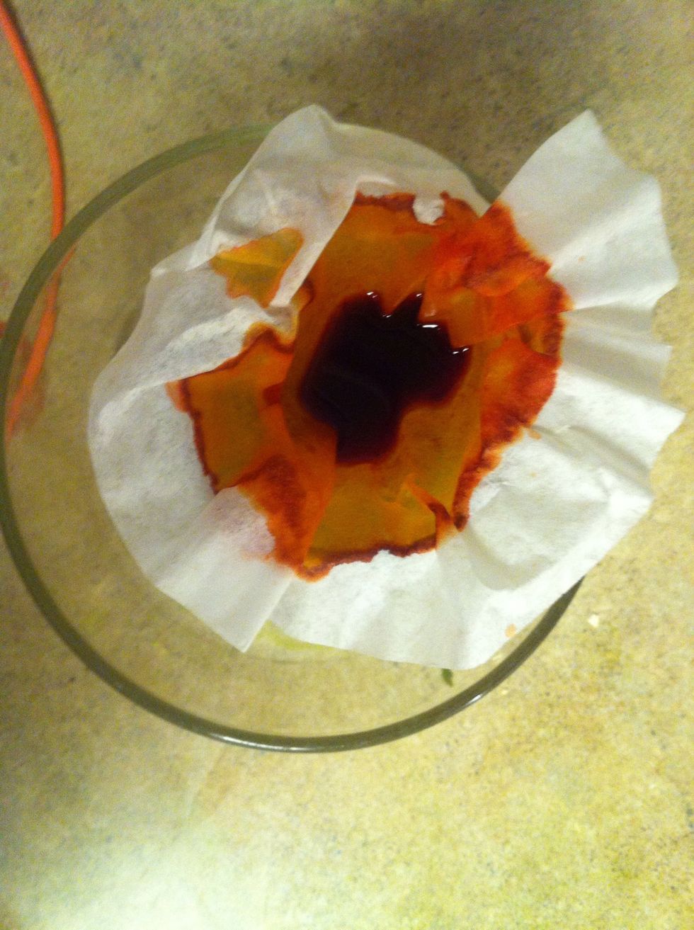 Put the coffee filter securely over the cup and start to slowly pour the mixture from the measuring cup into the glass cup.