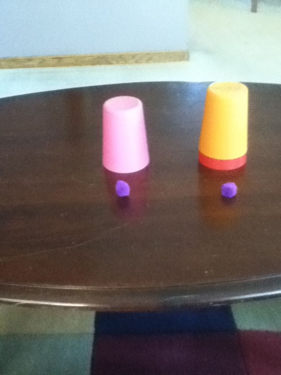 Put the cup that behind that puff ball on top of the cup