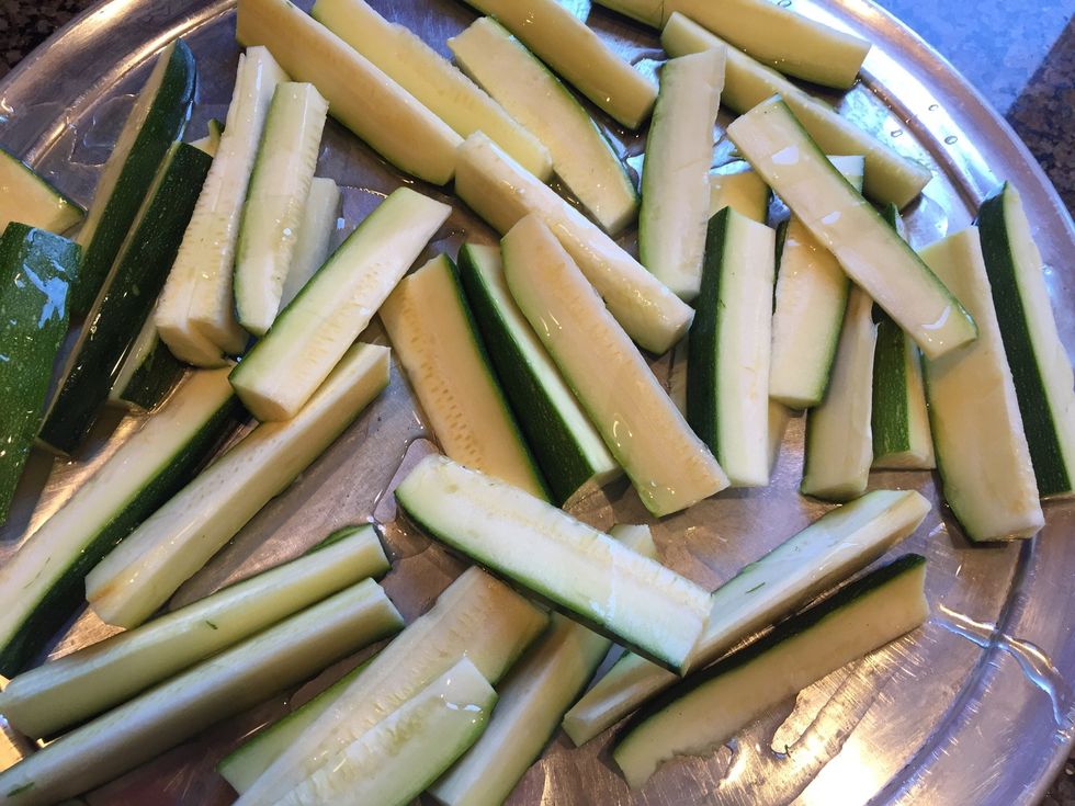 Put the cut zucchinis on a sheet pan and drizzle with olive oil.