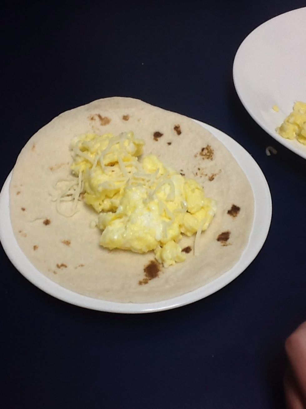 Put the eggs on the tortilla and add cheese, along with salt and pepper.