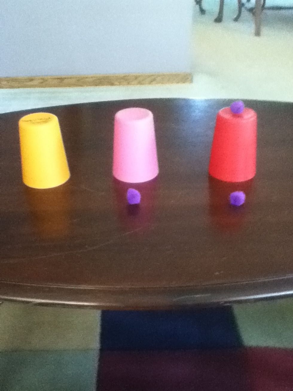 Put the farthest puff ball on the cup that has one puff ball underneath it