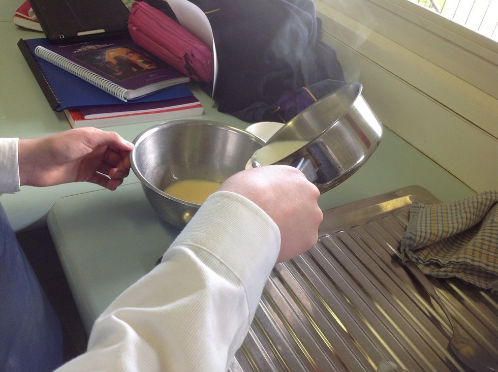 Put the flour, custard powder and 1/4 of the heated milk into a mixing bowl. Stir it all together. Put the rest of the milk back onto the heat.