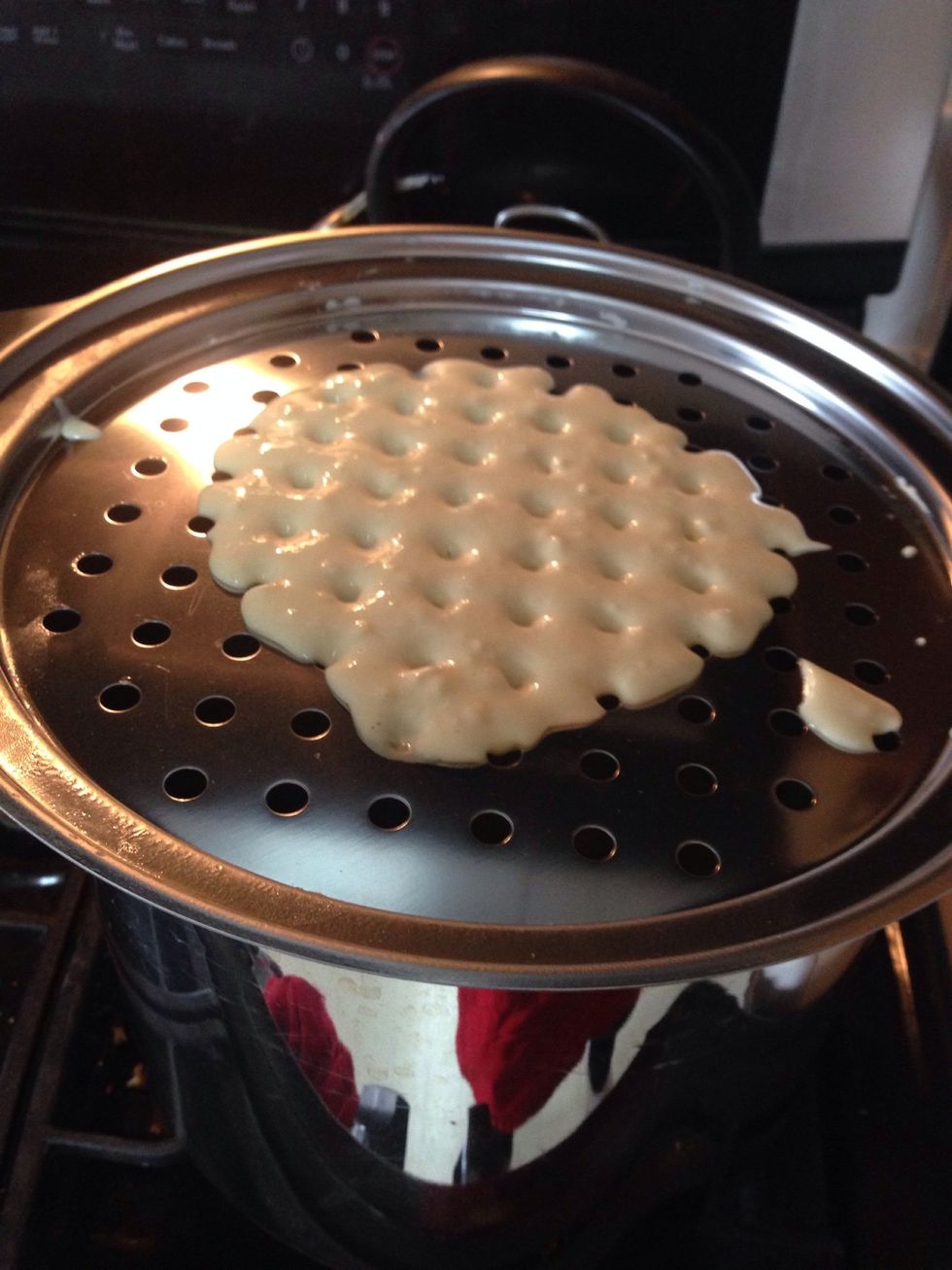 Put the grater on the pot and pour some dough on it