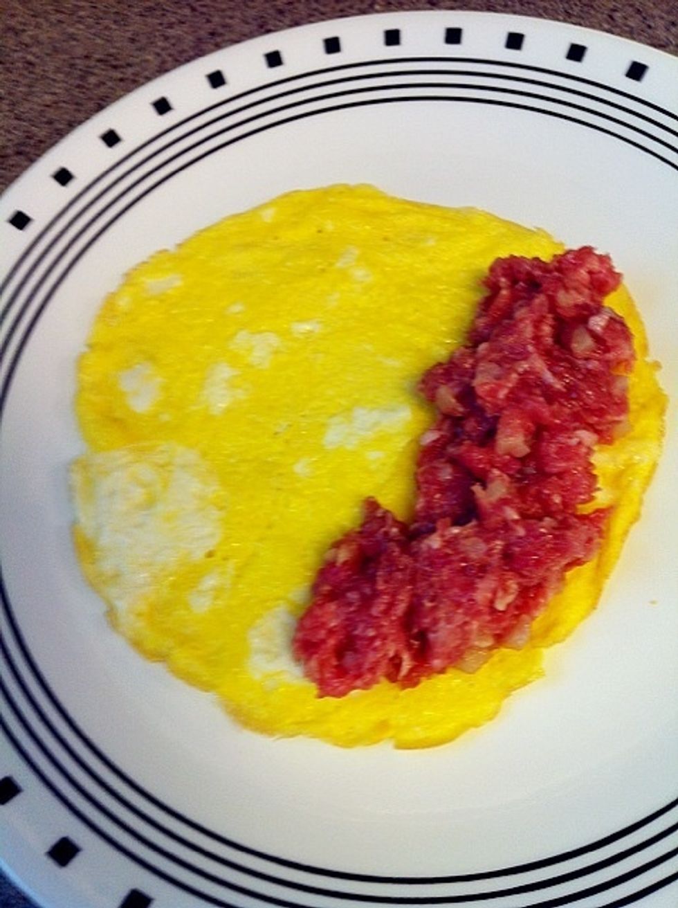 Put the half cooked eggs on a plate and add the ground pork as picture. Then, roll it carefully.