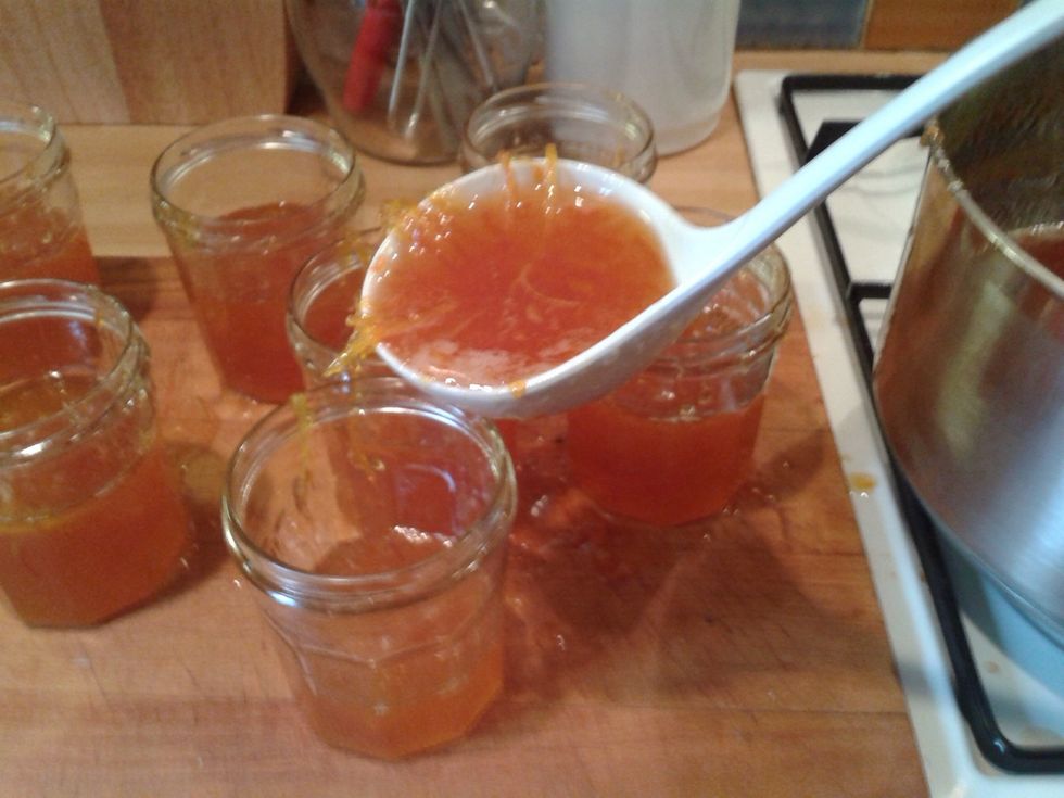 Put the hot jars on a board using oven gloves. Quickly fill the jars.