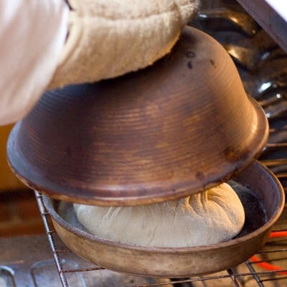 Put the lid on the la Cloche. If you are using a pizza stone, scatter some coarse corn meal on the stone before the bread dough goes on it to prevent sticking.