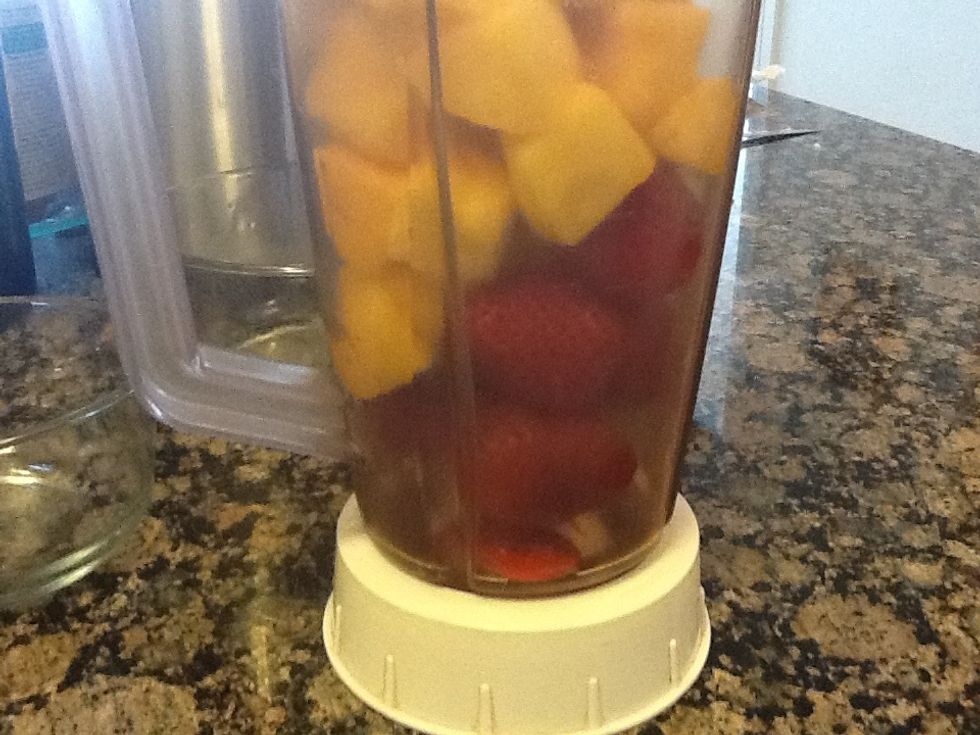 Put the mangos and strawberries into the blender.