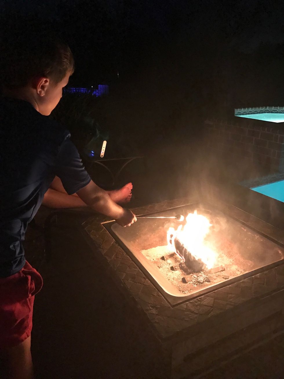 Put the marshmallow on the metal stick and cook over the fire.