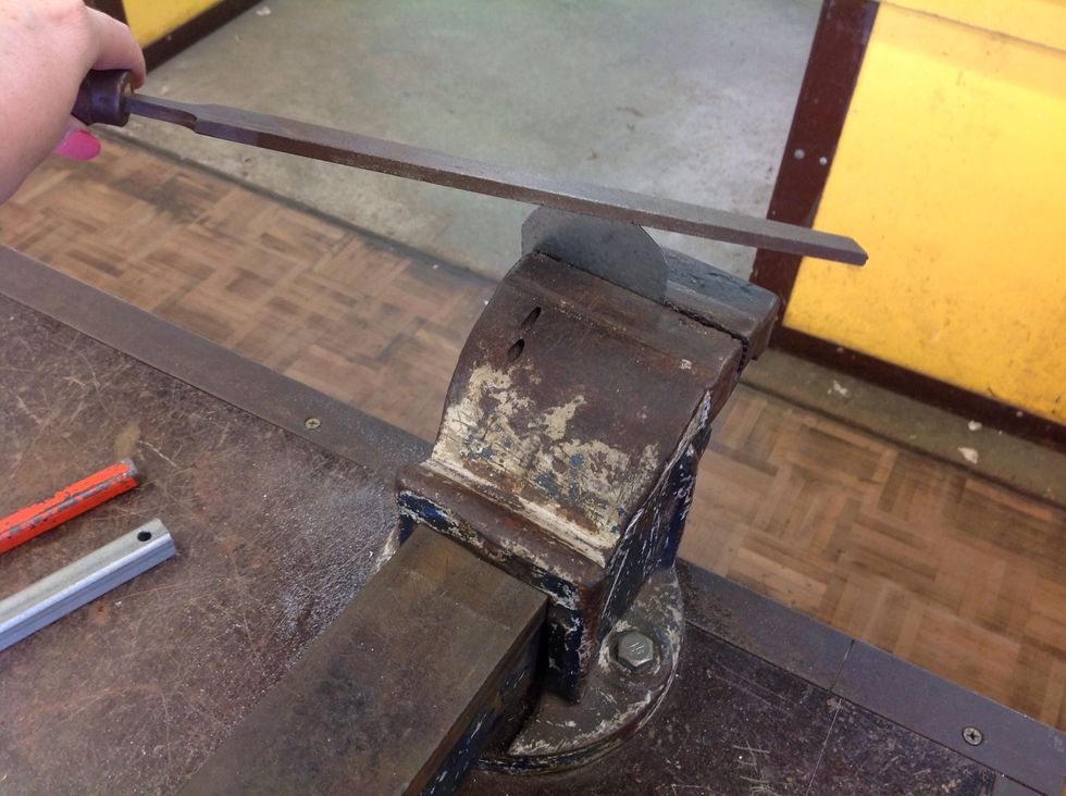 Put the metal in the vice. Get the file and smoothen the circle.