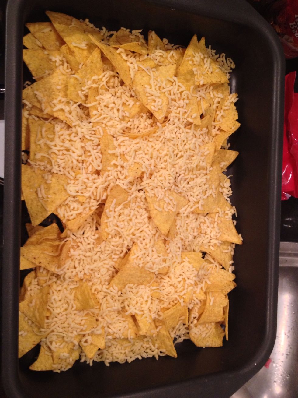 Put the nachos in a oven dish and sprinkle the cheese on it