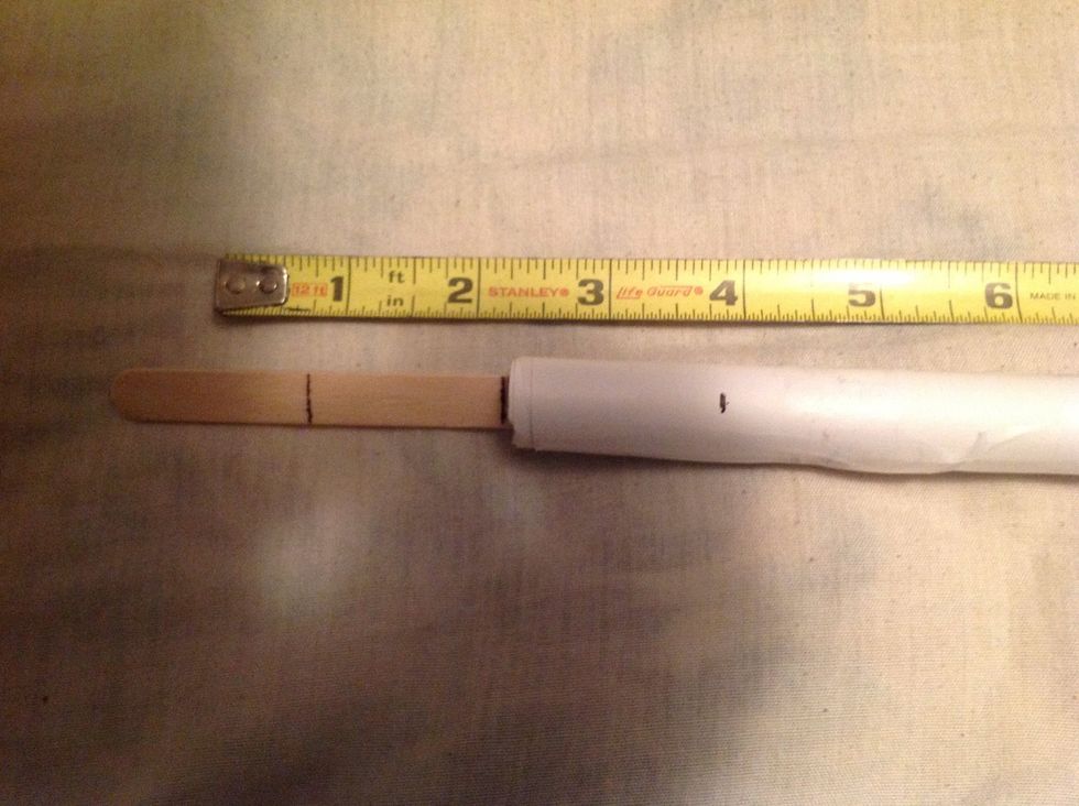 Put the one end of the popsicle stick inside the paper tube up to the mark that you made.