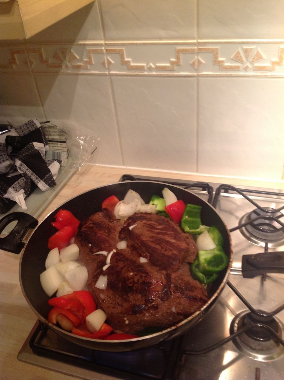 Put the onion, peppers and garlic in the pan with the beef. Keep the hob on high heat and after about 5 minutes half cover it with a lid to simmer. Stir from time to time.