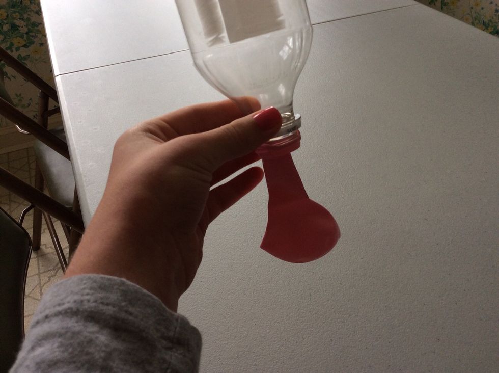 Put the opening of the balloon onto the water bottle opening