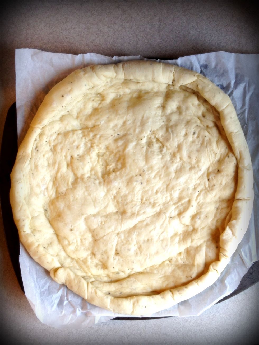 Put the pizza crust on parchment paper. I made my own and cooked it a few minutes before topping. You can buy pizza dough, or pre-made crusts like Boboli for example.