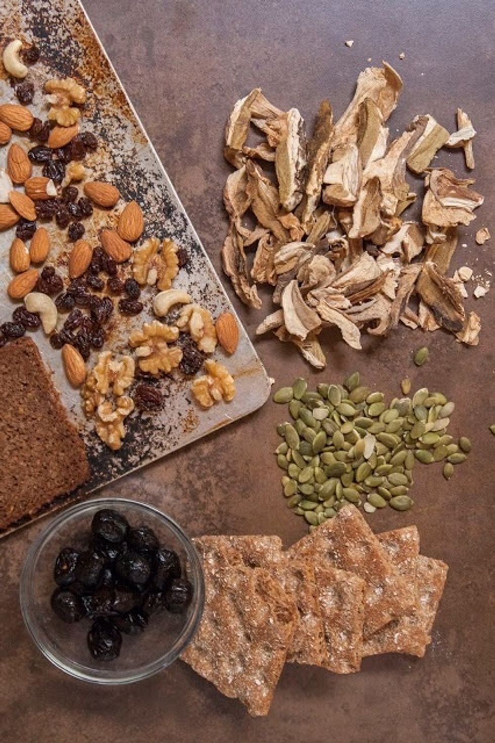 Put the raisins, mixed nuts, almonds and pumpernickle on a cookie sheet. Spread them in a single layer. Bake them in the oven for 30 to 45 minutes. It's done when the bread is crisp on top.