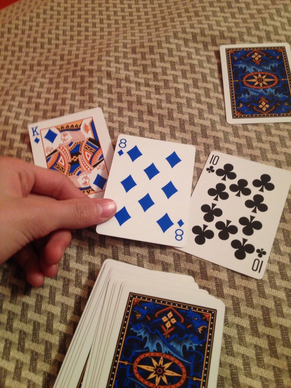 Put the rest of the cards down, now pick up the three cards one by one saying you don't think that it's their card. (Pick up the middle one last)