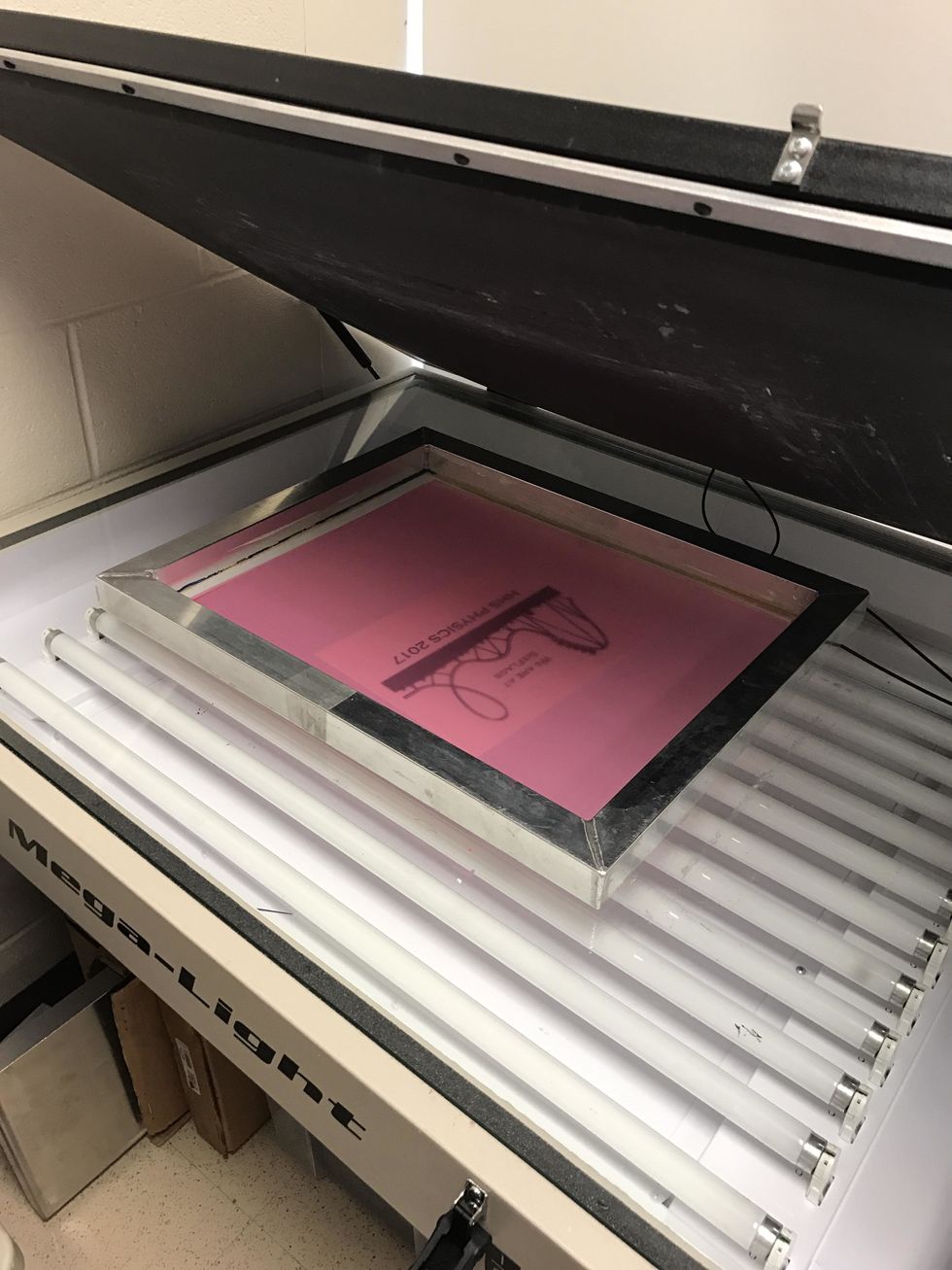 Put the screen face down in the light table. Put the strings on the screen, but not on the design. Close the top and secure it.