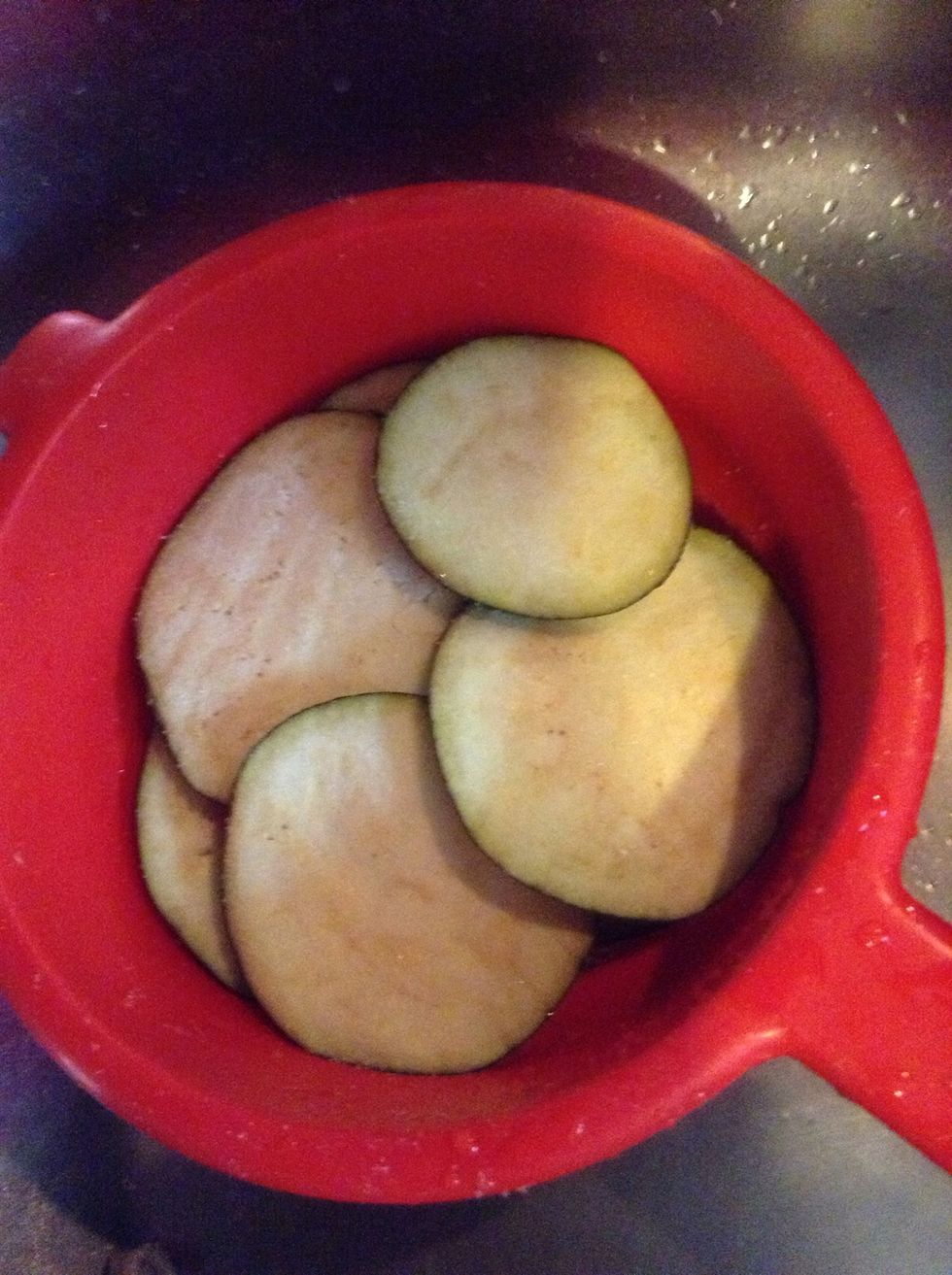 Put the slices in a colander and salt them. This step is important because salt drains your eggplants from water.