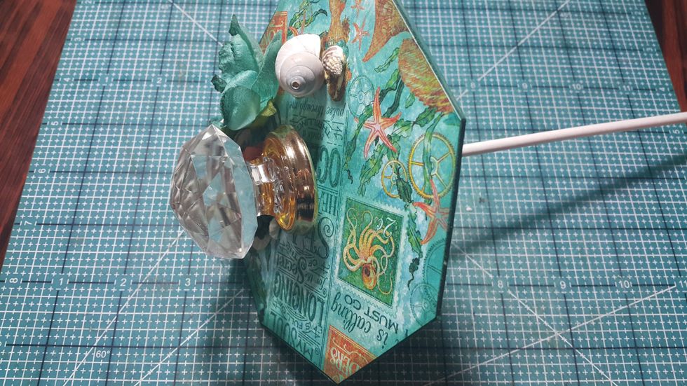 Put the stick through the octagon from step 4, which is already covered with papers on one side.