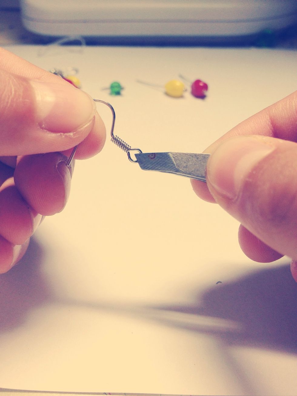 Put the tweezers/pliers inside the loop of the bottom of the earring hoop (the part that will go in your ear)