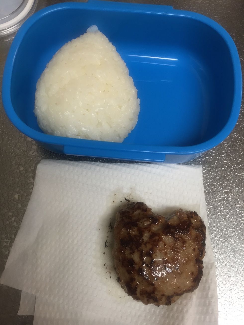 Put the unwrapped rice ball and cooked hamburger steak into the lunchbox.
