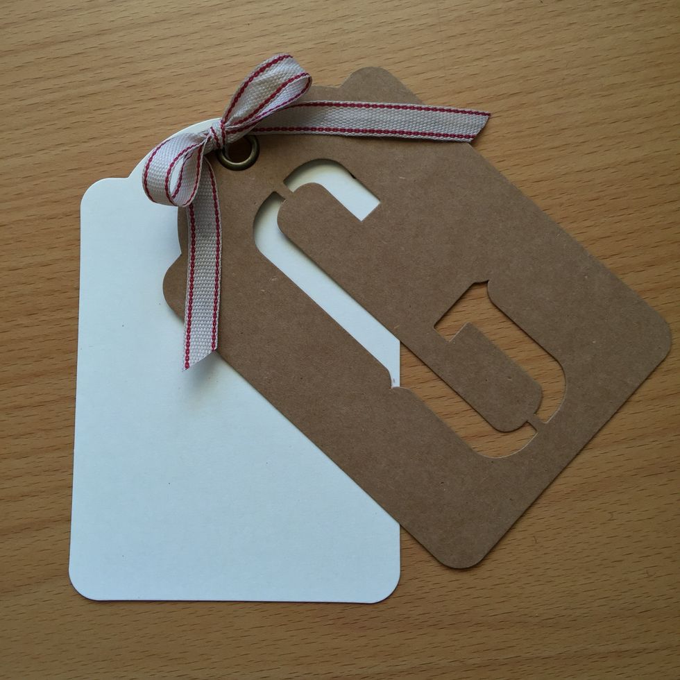 Put together two tags and lace them with a ribbon. Then we add all the embellishments on the cover.