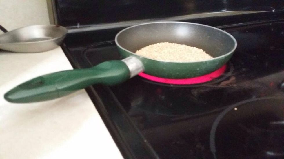 Put your 2 tablespoons of sesame seeds in a skillet. Turn the stove on high, and toast the sesame seeds. Keep toasting them until they are slightly brown.