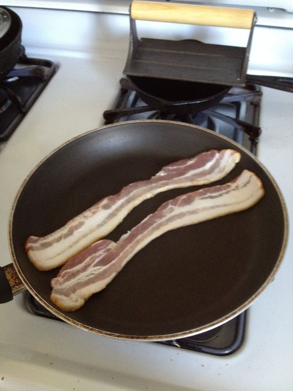 Put your bacon in a pan to fry. Some people cut up the bacon first but I find that method makes it hard to get evenly cooked, crispy bacon.