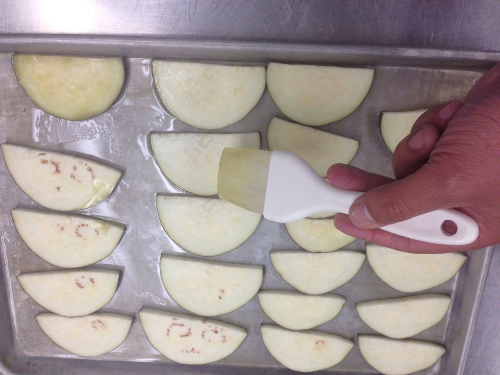 Put your eggplant slice on the pan and brush them with olive oil as well.