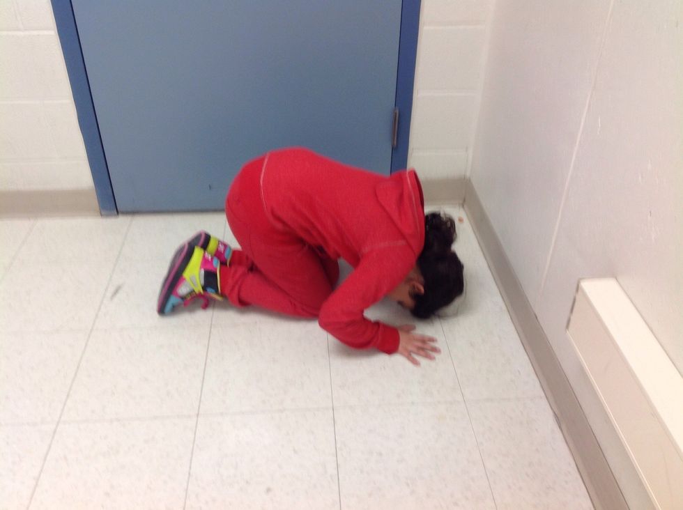 Put your hands and head on the mat and kneel on the floor.