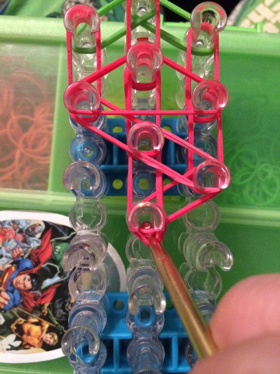 Put your hook in the center peg. Pull back the capping band and grab the first 2 rubber bands on top.