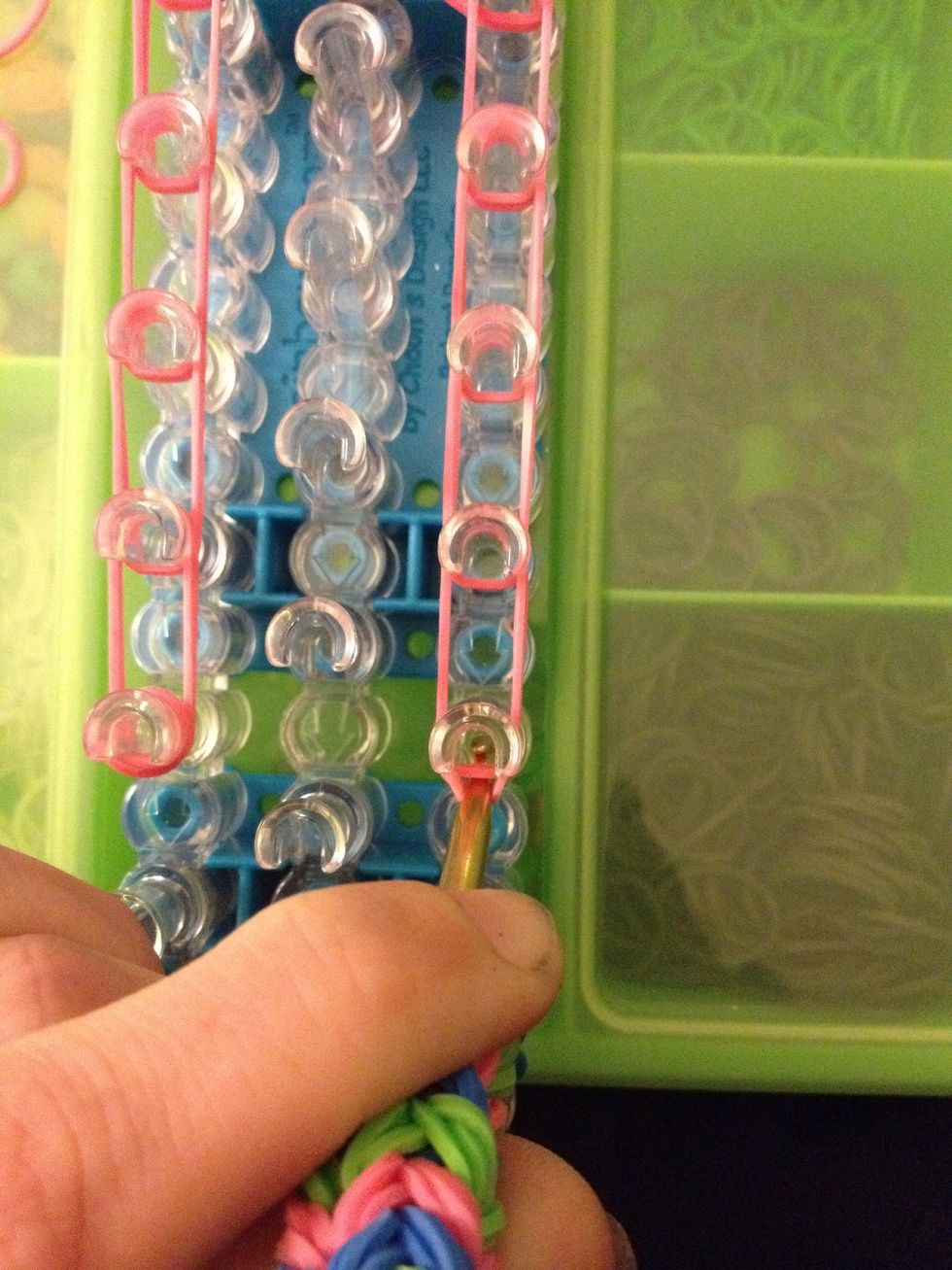 Put your hook in the peg. Pull back the capping band and grab the two rubber bands. Move them to the next peg.