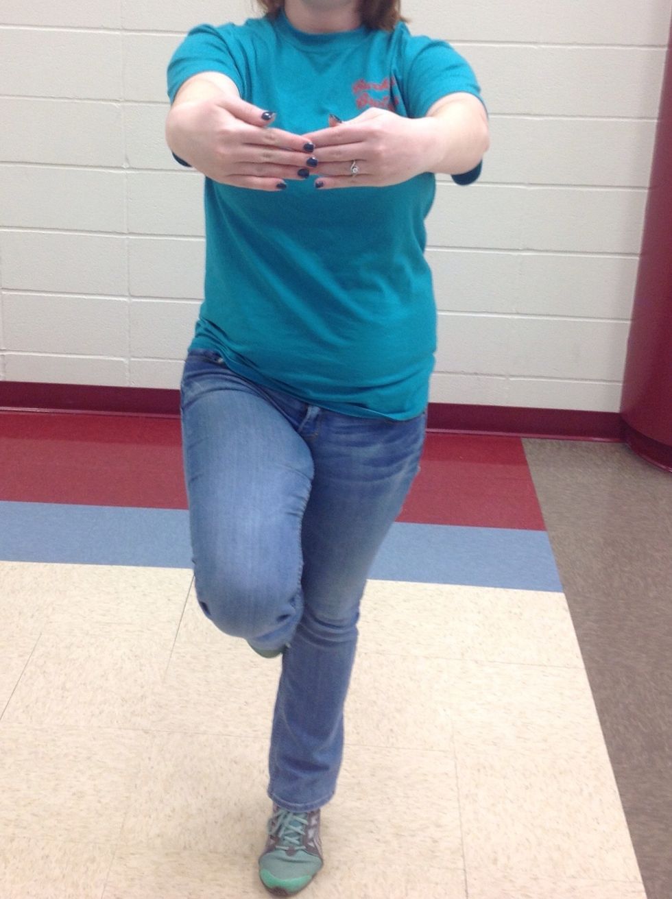 Put your right foot to your left knee and hold your arms in front of you like you're holding a beach ball.