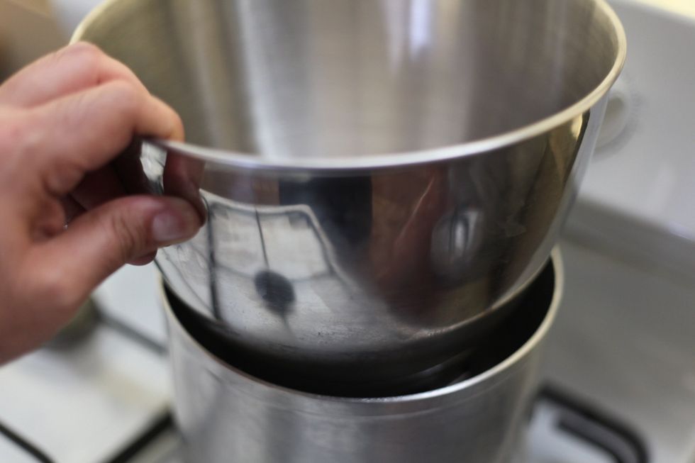 Put your tempering bowl over the already boiled water and let it just warm up. Pour the 600ml of cream into the bowl and leave it. Don't turn on the fire yet. Have a whisk ready. Chocolate time...