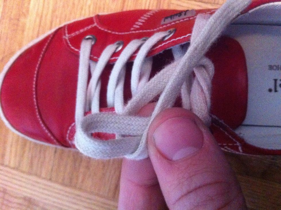 Putting the other loose lace around the front of the loop then towards the back of the loop (towards yourself)