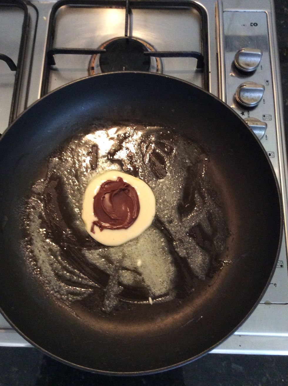 Quickly add 1 frozen Nutella disk onto the pancake mixture.