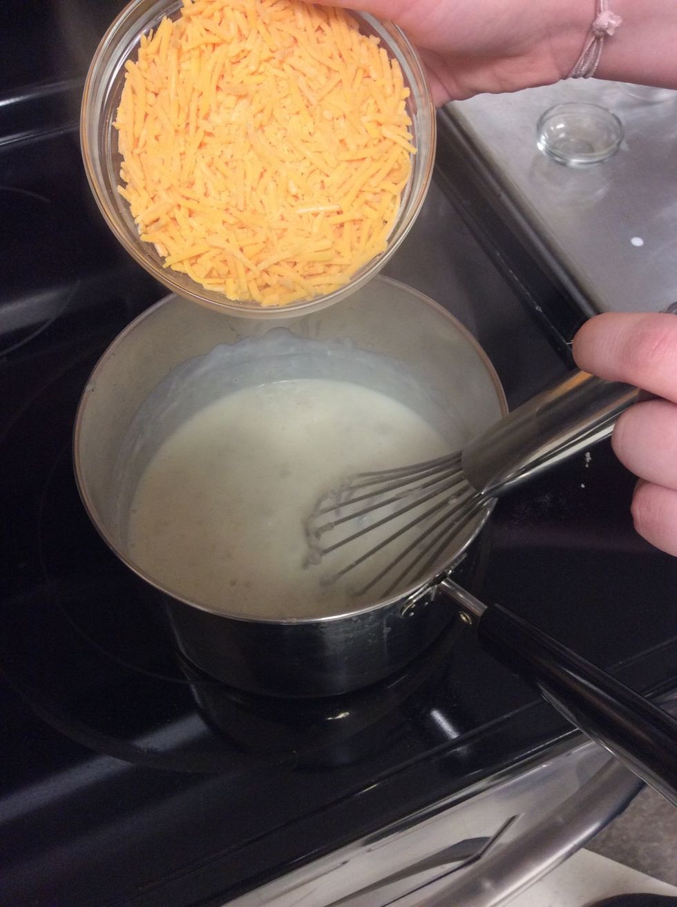 Raise sauce to medium-high heat as you add in 8 oz of grated extra sharp cheddar.
