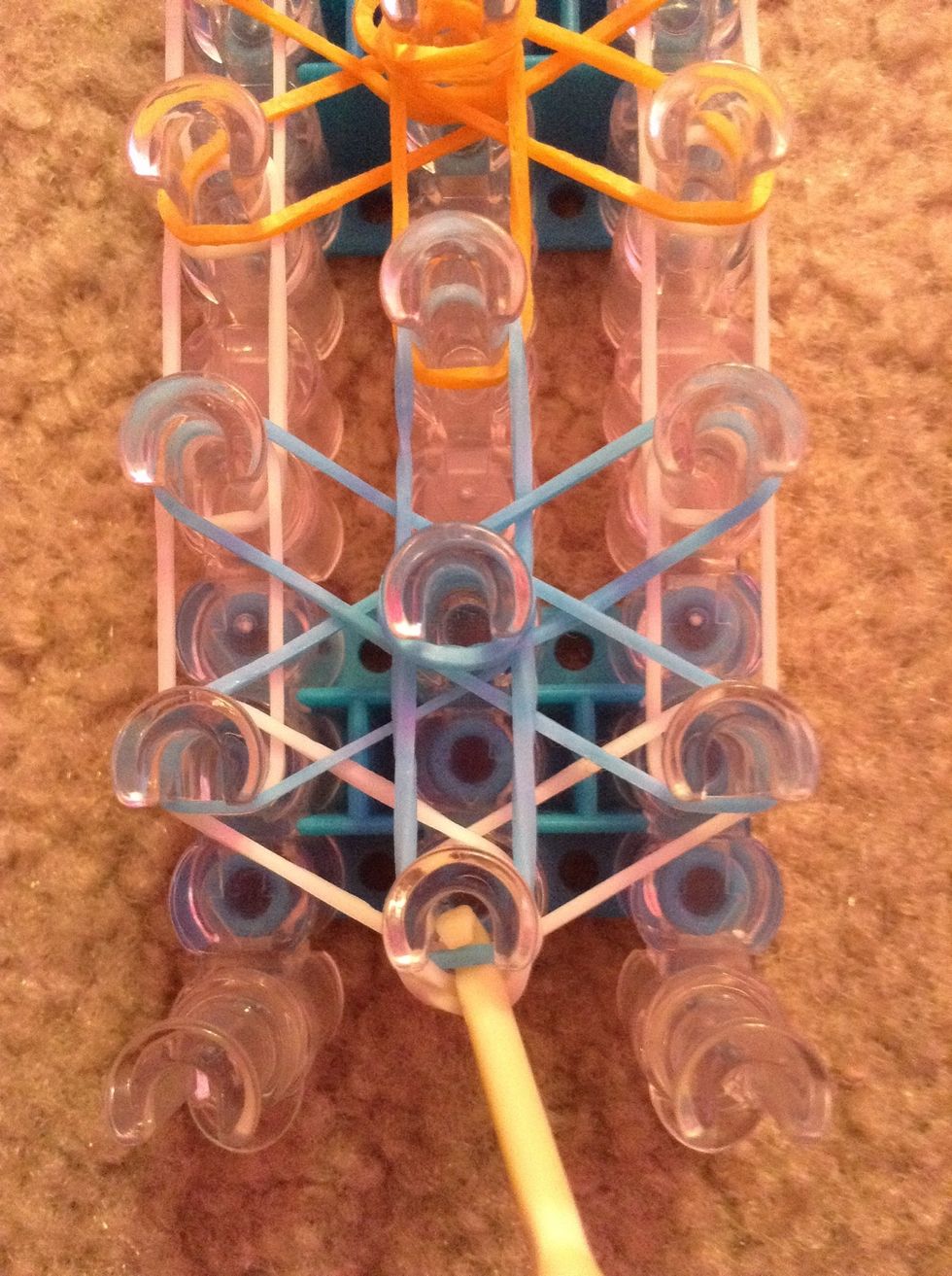 Reach down into the cap band and pull over the first blue band.
